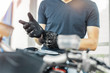 © Akaberka - Close up of biker putting on black gloves and sitting on motorcycle.