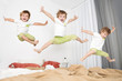 Cheerful little boy  jumping on bed at home. lot of children.
