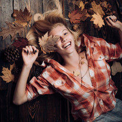 Happy young woman are preparing for autumn sunny day. Funny fac . Smile girl lies on wooden background and dreams of warm autumn. Black friday shopping. Top view.