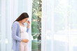© New Africa - Young beautiful pregnant woman near window at home