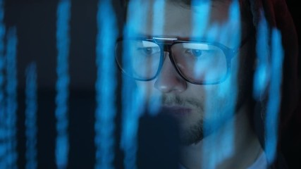 Portrait of cyberpunk young man looking into the monitor screen in the darkness.