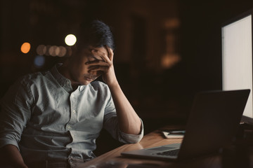 Exhausted Asian businessman working at his desk late at night