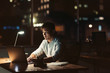 © mavoimages - Young Asian businessman working late at night at his desk