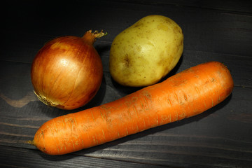 Wall Mural - Onions, carrots and potatoes on a dark background