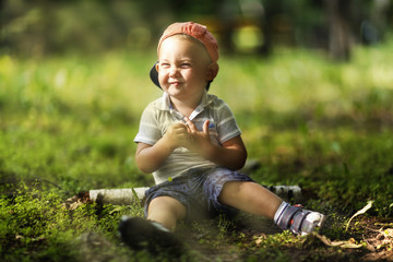 boy sitting on the green ground in the forest