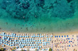 Topdown Sicht auf den Psarou Strand mit dicht gestellten Sonnenschirmen an türkisem Meer, Mykonos, Griechenland