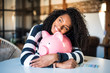 Black woman hugging her piggy bank