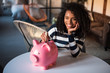 © DavidPrado - Black woman with saving piggy bank