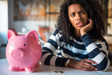 Thoughtful Confused Black Woman With Piggy Bank