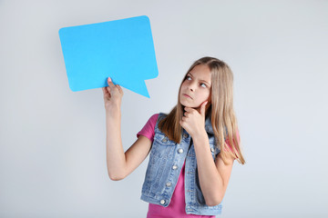 Wall Mural - Young girl holding speech bubble on grey background