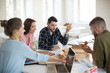 Group of young men and women happily eating pizza together in office. Young creative people spending time at work