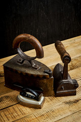 Wall Mural - three old rusty iron on a bright wooden table next to a black wall