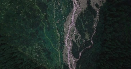 Aerial View From Above Of A Stream That Flows From The Glacier At The Foot Of The Mountains Through The Trees And Valleys
