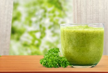 Wall Mural - Green vegetable smoothies in glasses on wooden