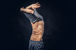 © Fxquadro - Stylish ectomorph bodybuilder with stylish hair takes off his shirt on the dark background.