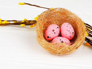 pink Easter eggs in nest on white wooden background, copy space