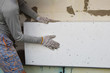 Man installing rigid styrofoam insulation board for energy saving on exterior wall of building. Rigid extruded polystyrene insulation for house improvement.