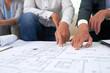 © DragonImages - Real estate agent showing building blueprint to client at meeting