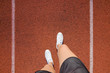 Young woman's legs in white shoes standing on stadium track in summer day. Daily outdoor active lifestyle. Enjoying sport. Training time. Point of view shot. Part of body.