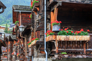 Wall Mural - Beautiful traditional wooden houses in the streets of the alpine village Grimentz, Switzerland, in the canton Valais, municipality Anniviers, with geranium flowers on the balconies
