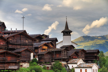 Wall Mural - Beautiful cityscape of the alpine village Grimentz, Switzerland, with traditional wooden houses and church tower in summer