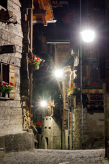 Wall Mural - Beautiful traditional houses in the streets of the village Grimentz, Switzerland, canton Valais, municipality Anniviers, at night with geranium flowers on the balconies illuminated by streetlights