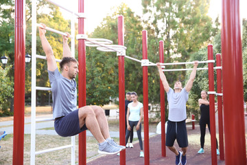 Group of sporty people training on athletic field outdoors