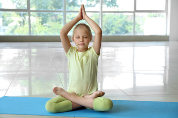 Wall Mural - Little girl practicing yoga indoors