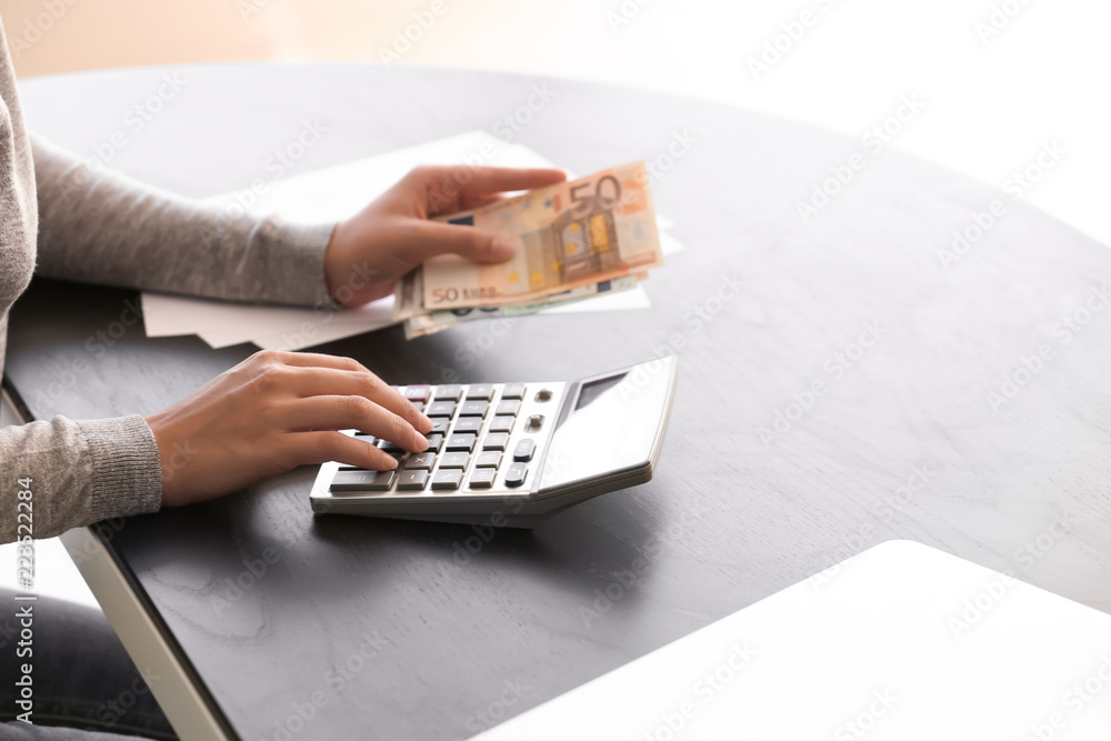 Young woman counting money while sitting at table, closeup