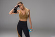 © LIGHTFIELD STUDIOS - athletic young woman wiping sweat on forehead with towel on grey