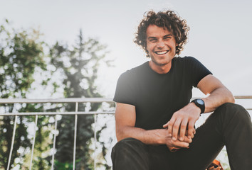 low view shot of happy stylish young man wears black t-shirt and wirstwatch on the street. happy smi