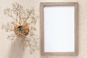 Terrazzo desk with a wooden mockup frame and a vase with dried white flowers