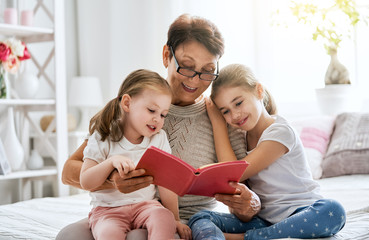 Wall Mural - Grandmother reading a book to granddaughters