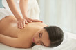 © DragonImages - Unrecognizable massage therapist rubbing back of beautiful lady while working in spa salon