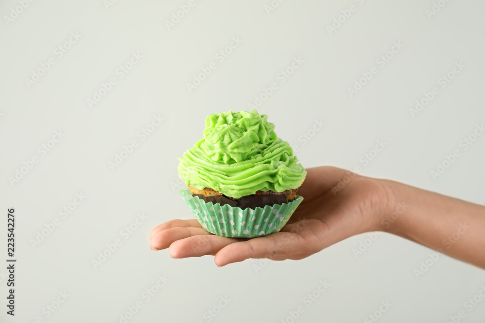 Woman holding tasty cupcake on white background