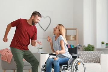 Wall Mural - Beautiful woman in wheelchair with man dancing at home