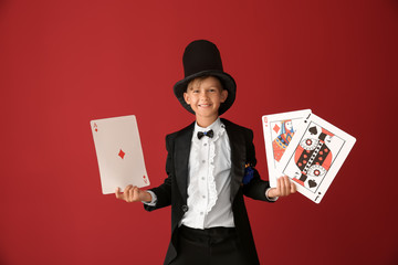 Wall Mural - Cute little magician with cards on color background