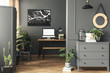 Black poster on grey wall above desk with mockup in home office interior with mirror. Real photo