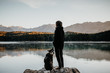 Frau steht mit ihrem Hund am Ufer des Eibsee in Bayern 