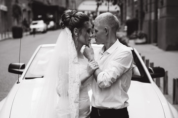 A newlyweds trip in the car. The groom invites the bride in a white cabriolet.