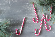 Candy Canes And Spruce Branches On A Gray Concrete Background, Christmas Concept With Place For Text.