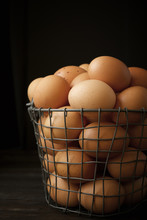 Close-up Of Brown Eggs In Basket On Table Against Black Background