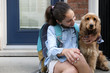 © Cavan Images - Smiling girl with backpack sitting by Cocker Spaniel on porch