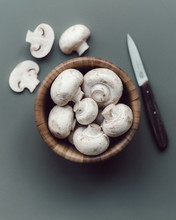 Overhead View Of White Mushrooms In Bowl With Kitchen Knife On Table