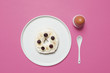 Overhead view of bun with fruits and egg on pink background