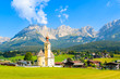 Church on green meadow in Going am Wilden Kaiser mountain village on sunny summer day, Tyrol, Austria