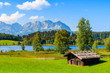 Wooden hut on green meadow against Alps mountains near Schwarzsee lake on sunny beautiful summer day near Kitzbuhel, Tyrol, Austria