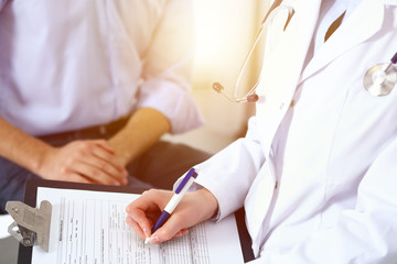 Female doctor holding application form while consulting man patient in hospital. Medicine and healthcare concept