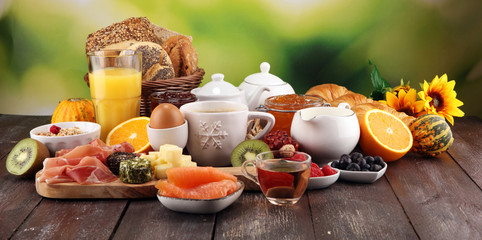 breakfast on table with bread buns, croissants, coffe and juice.