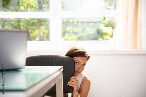 Fotografía Frightened Businesswoman Hiding Behind Chair